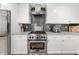 Close-up of a kitchen featuring white cabinets, stainless steel appliances, and gray tile backsplash at 2110 Augusta Se Dr # 204, Marietta, GA 30067