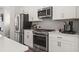 Modern kitchen featuring stainless steel appliances, white cabinets, and gray backsplash at 67 Wilder Ridge Way, Lawrenceville, GA 30044