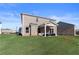 Spacious backyard featuring a covered patio and green lawn with brick home at 209 Chiswick Loop, Stockbridge, GA 30281