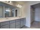 Bright bathroom featuring double sinks, gray cabinetry, expansive mirror, and glass-enclosed shower at 209 Chiswick Loop, Stockbridge, GA 30281