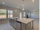 Open kitchen boasts a gray island with a stainless steel sink and views to the living room with a fireplace at 209 Chiswick Loop, Stockbridge, GA 30281
