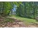Expansive backyard with lush greenery, tall trees, and glimpses of a home through the woods at 3131 Lee Cir, Buford, GA 30518