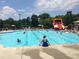 A vibrant community pool with families enjoying a summer day, featuring a waterslide and lounge areas at 5157 Wellisford Ct, Suwanee, GA 30024