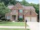 Charming two-story brick home featuring a well-manicured lawn, mature trees, and a two-car garage at 5157 Wellisford Ct, Suwanee, GA 30024