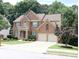 Traditional brick home with a two-car garage, front yard landscaping, and a second-story balcony at 5157 Wellisford Ct, Suwanee, GA 30024