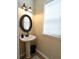 Well-lit powder room featuring a pedestal sink, an oval mirror, and a window with horizontal blinds at 5157 Wellisford Ct, Suwanee, GA 30024