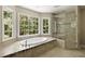 Relaxing bathroom featuring a soaking tub, a separate glass shower, and picture windows at 1956 Regents Way, Marietta, GA 30062