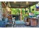 View of covered back porch with seating, ceiling fan, plants, and view to backyard trees at 1784 Virginia Grove Ln, Lawrenceville, GA 30045