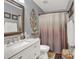Bathroom with a vanity, framed mirror, decorative shelving and shower with mauve and tan fabric curtain at 1784 Virginia Grove Ln, Lawrenceville, GA 30045