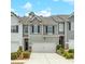 Charming townhome with gray and white siding, a two car garage and lovely landscaping at 738 Woodstock Grove Dr, Woodstock, GA 30188