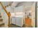 Convenient laundry area featuring a washer, dryer, storage cabinets, and tile flooring, located near the stairs at 6300 Blackwater Trl, Atlanta, GA 30328