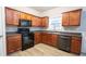 Stylish kitchen featuring cherry wood cabinets, sleek black appliances, and wood-look floors at 3165 Creston Park Ct, Duluth, GA 30096