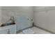 A well-lit laundry room with stainless steel sink, marble tile accent wall, and white cabinets at 4208 Sierra Creek Ct, Hoschton, GA 30548