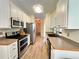 Galley style kitchen with stainless steel appliances, white cabinets, and wood look flooring at 235 Pirkle Ct, Cumming, GA 30040