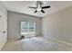 Bright, carpeted bedroom featuring a ceiling fan and a window with a view of the outdoors at 6010 Somerset Ct, Suwanee, GA 30024