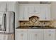 Kitchen with stainless steel refrigerator, white cabinets, granite counters, and tile backsplash at 6010 Somerset Ct, Suwanee, GA 30024