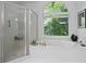 Bright bathroom features a glass shower and luxurious soaking tub with a large window offering backyard views at 12160 Oak Hollow Way, Alpharetta, GA 30005