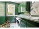 Laundry room featuring green cabinets, sink, washer and dryer, window and decor on a light-colored floor at 12160 Oak Hollow Way, Alpharetta, GA 30005