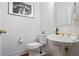 This powder room has a pedestal sink, a commode, and a piece of framed art on the wall at 12160 Oak Hollow Way, Alpharetta, GA 30005