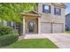 Inviting front entrance featuring a covered porch, brick facade, and a two-car attached garage at 219 Sleepy Way, Canton, GA 30114