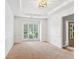Formal dining room with tray ceiling, large window, and neutral carpet at 2720 Stillwater Lake Ln, Marietta, GA 30066