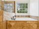 Relaxing bathroom features a soaking tub with tile surround and views of nature at 2720 Stillwater Lake Ln, Marietta, GA 30066