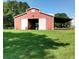 Exterior view of a charming red barn featuring a lean-to, sliding doors, and green grass at 4393 Cannon Rd, Loganville, GA 30052