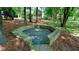 Stone fire pit area surrounded by mature trees and natural foliage, great for outdoors gathering at 4393 Cannon Rd, Loganville, GA 30052