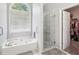 Bright bathroom with jacuzzi tub, glass shower, and walk-in closet at 1010 Capella Creek Way, Grayson, GA 30017
