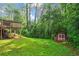 Beautiful backyard with lush green grass, mature trees, a wood shed, and elevated deck at 2703 Carolyn Se Dr, Smyrna, GA 30080