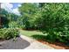 Well-manicured backyard featuring a lush lawn, mature trees, and a charming walking path at 5004 Haralson Sw Way, Lilburn, GA 30047