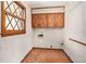 A laundry room featuring wooden cabinets, a window, and red brick flooring at 5419 Ahyoka Dr, Morrow, GA 30260