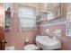 Classic pink bathroom with tiled walls, vanity, and window with lace curtains at 2880 Sherwood Se Rd, Smyrna, GA 30082