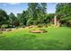 Lush green front lawn featuring mature trees, manicured shrubbery, and a stone-lined garden at 3152 Sycamore Ln, Marietta, GA 30066