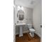 Elegant half bath featuring a pedestal sink, oval mirror, and wood flooring at 2118 Iverson Se Dr, Smyrna, GA 30080