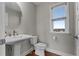 Charming powder room with pedestal sink, round mirror, and natural light from window at 2118 Iverson Se Dr, Smyrna, GA 30080