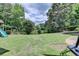 Landscaped backyard with lush green lawn, mature trees, and playground at 2875 Daniel Park Run, Dacula, GA 30019