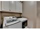Laundry room featuring modern, front-load washer and dryer units beneath white cabinets, streamlining household chores at 2875 Daniel Park Run, Dacula, GA 30019