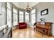 Bright sitting room features hardwood floors, comfortable armchair, piano, chandelier, and large windows at 2875 Daniel Park Run, Dacula, GA 30019