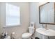Cozy half-bathroom with white pedestal sink, toilet, mirror, and natural light from window at 2247 Pink Hawthorn Dr, Buford, GA 30518