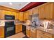 Cozy kitchen with warm wood cabinets, granite countertops, and black appliances with a red accent wall at 3819 Courson St, Marietta, GA 30066