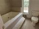 Bright bathroom featuring a large soaking tub, tile surround, and window at 4968 Twin Branches Way, Dunwoody, GA 30338