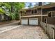 View of the house with a two-car garage and driveway surrounded by trees at 4968 Twin Branches Way, Dunwoody, GA 30338