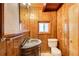 Bathroom features wood paneled walls, dark wood vanity, ornate sink, toilet, and small window at 504 N Little Victoria Rd, Woodstock, GA 30189