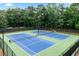 View of well-maintained tennis courts surrounded by a fence and mature trees in a residential community at 1297 Hadaway Trl, Lawrenceville, GA 30043