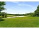 Expansive backyard featuring a tranquil pond, green grass, and mature trees at 833 Hines Rd, Moreland, GA 30259