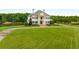 Elegant two-story home featuring a stately entrance, lush lawn, and a serene pond view at 833 Hines Rd, Moreland, GA 30259