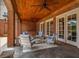 Covered outdoor living space with stained wood ceiling and brick columns provides serene poolside views and comfortable seating at 833 Hines Rd, Moreland, GA 30259