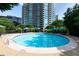 Outdoor swimming pool surrounded by lounge chairs, lush greenery, and blue umbrellas at 700 Park Regency Ne Pl # 1605, Atlanta, GA 30326