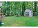 Expansive, tree-lined backyard with lush lawn, storage shed and bordered by mature trees at 2802 Leisure Woods Ln, Decatur, GA 30034